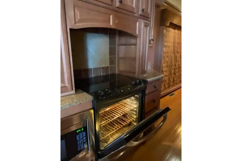 Slide: The Image of Kitchen island with granite countertop, open dishwasher, and wooden cabinets in a Summerset 21' x 106' model. - 312