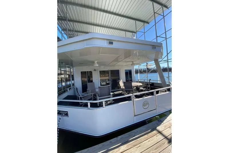 Slide: The Image of 2007 Summerset houseboat, 21' x 106', docked under a metal canopy on a sunny day. - 87