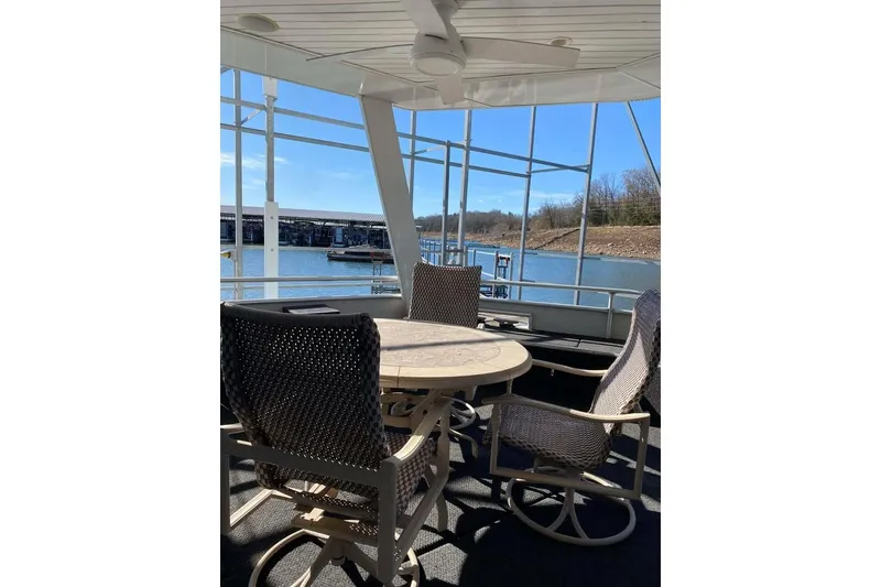 Slide: The Image of Summerset 21' x 106' 2007 houseboat with outdoor seating, docked by a serene lake. - 91