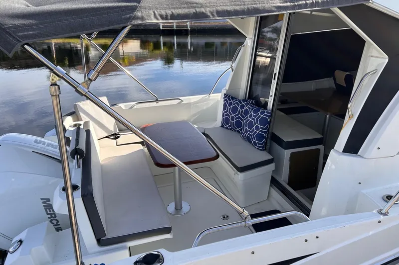 Slide: The Image of 2021 Beneteau Antares 8 boat interior with seating, table, and cushions by the water. - 10