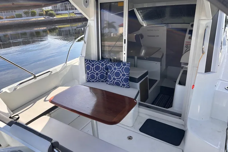 Slide: The Image of 2021 Beneteau Antares 8 boat interior with seating, table, and cushions by the water. - 12