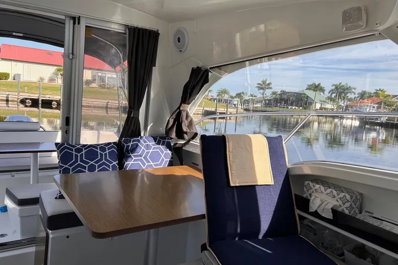 Slide: The Image of Interior of 2021 Beneteau Antares 8 boat with table, seating, and waterfront view. - 18