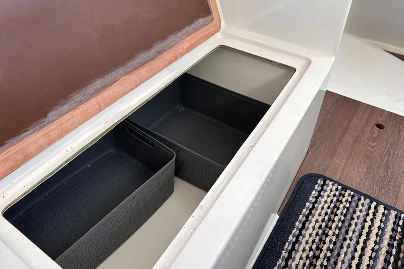 Slide: The Image of Storage compartment on 2021 Beneteau Antares 8 boat with two black bins and wooden flooring. - 31