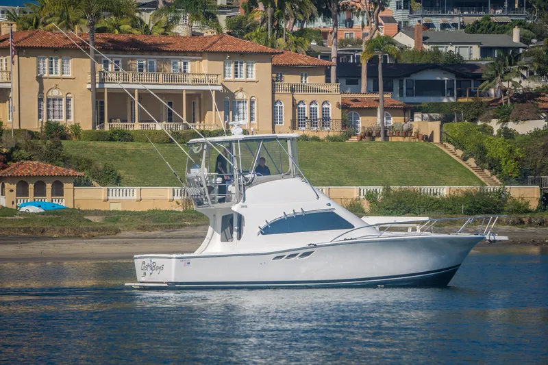 Slide: The Image of 2002 Luhrs 36 Convertible yacht cruising near luxurious waterfront homes. - 2