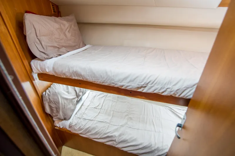 Slide: The Image of Bunk beds in 2002 Luhrs 36 Convertible yacht cabin, featuring wooden interior and white bedding. - 23