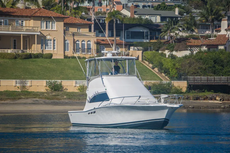 Slide: The Image of 2002 Luhrs 36 Convertible yacht cruising near luxurious waterfront homes. - 3
