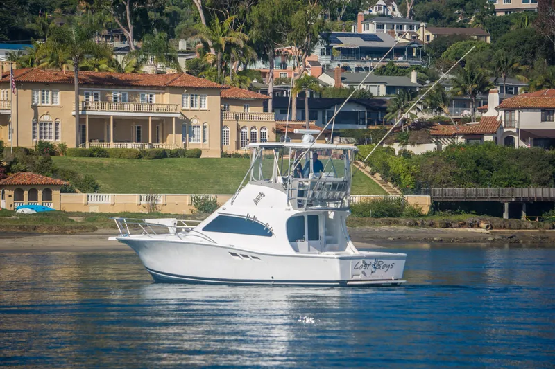 Slide: The Image of 2002 Luhrs 36 Convertible yacht on calm water near luxury waterfront homes. - 4