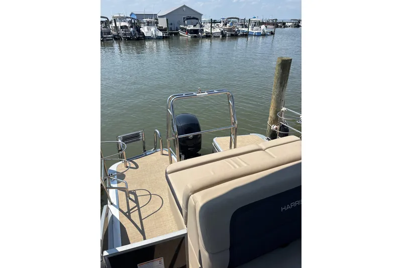 Slide: The Image of 2024 Harris HCX23 pontoon boat docked at marina with calm water and clear sky. - 11