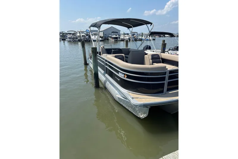 Slide: The Image of 2024 Harris HCX23 pontoon boat docked at marina under clear blue sky. - 3