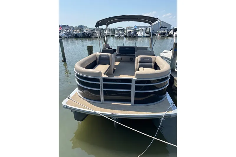 Slide: The Image of 2024 Harris HCX23 pontoon boat docked at marina, featuring spacious seating and sleek design. - 5