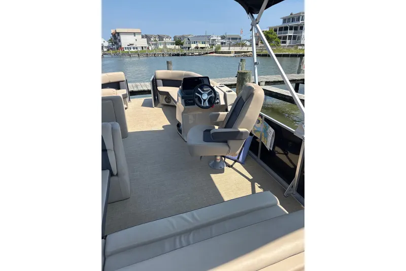 Slide: The Image of 2024 Harris HCX23 boat interior with helm, seating, and waterfront view. - 8