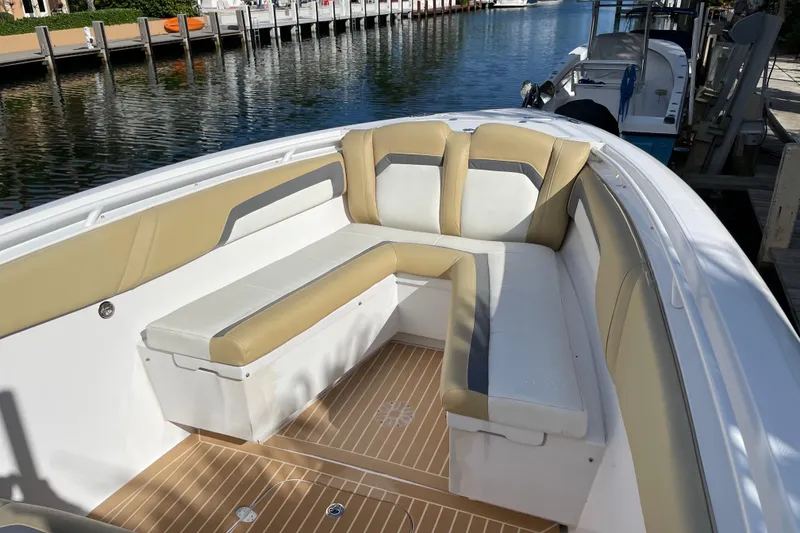 Slide: The Image of 2014 Powerplay Powerboats 35 Open with beige and white seating, docked by a calm waterfront. - 21