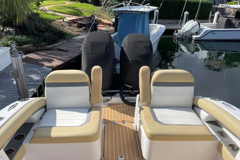 Slide: The Image of 2014 Powerplay Powerboats 35 Open with cushioned seating, docked near a garden pathway. - 8