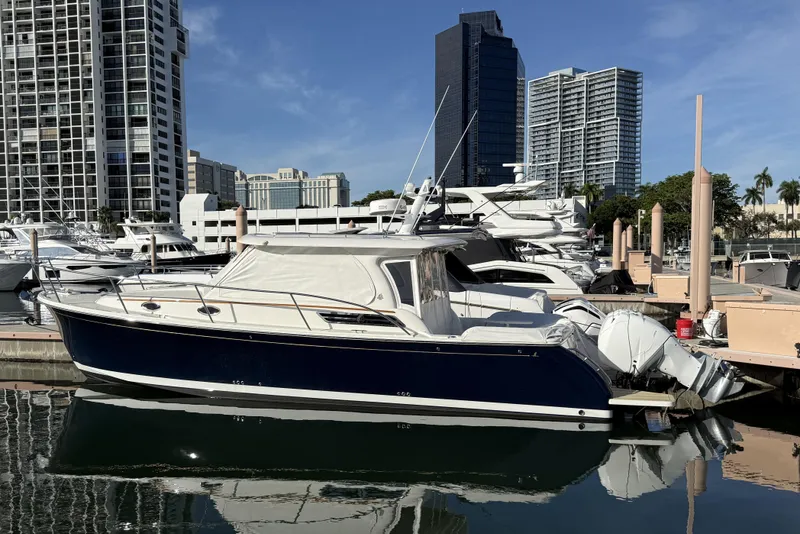 Slide: The Image of 2022 Back Cove 34O boat docked in a marina with city skyline background. - 19