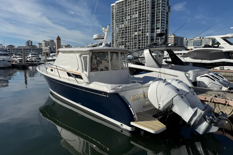 Slide: The Image of 2022 Back Cove 34O boat docked in marina, city skyline in background. - 20