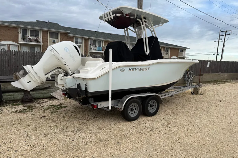 Slide: The Image of 2023 Key West 219 FS boat on trailer, parked outdoors near residential area. - 2