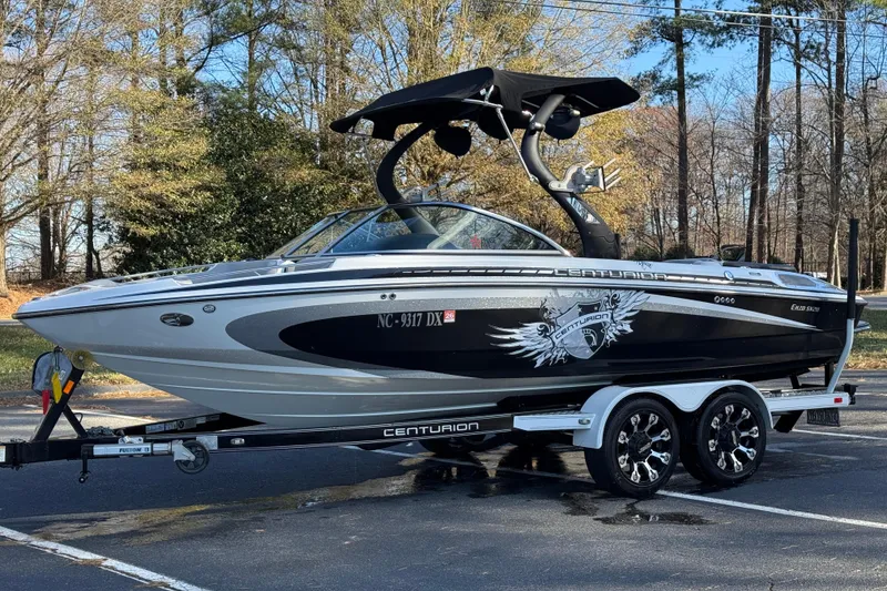 Slide: The Image of 2012 Centurion Enzo SV211 boat on trailer, parked outdoors with trees in background. - 22