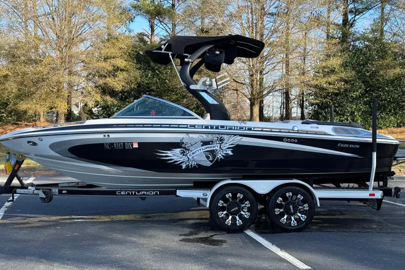 Slide: The Image of 2012 Centurion Enzo SV211 boat on trailer, parked in a wooded area. - 23
