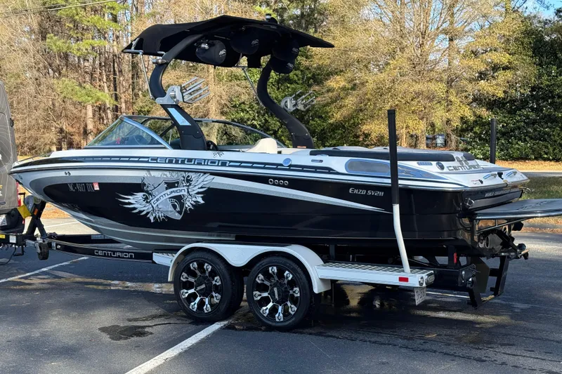 Slide: The Image of 2012 Centurion Enzo SV211 boat on trailer, black and white design, parked outdoors. - 24