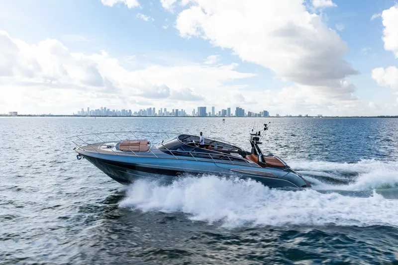 Slide: The Image of 2021 Riva 56 Rivale yacht cruising on open water with city skyline backdrop. - 5