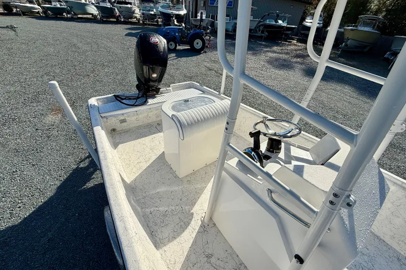 Slide: The Image of 2023 Rabco R21 boat with outboard motor and steering console, parked on gravel. - 21