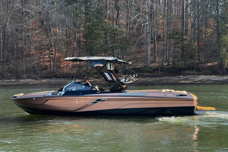Slide: The Image of 2025 Centurion Ri265 boat cruising on a lake with forested background. - 10