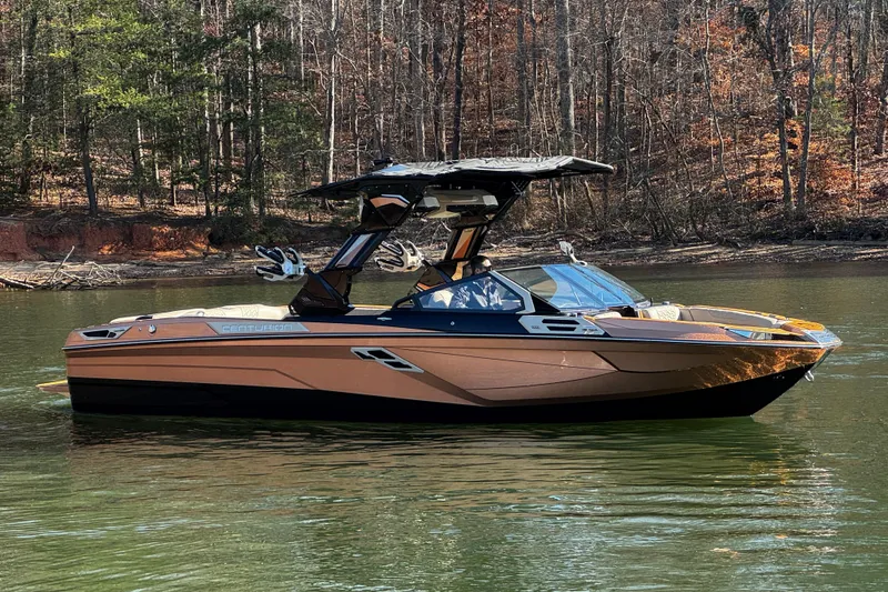 Slide: The Image of 2025 Centurion Ri265 boat on a calm lake with forested background. - 2