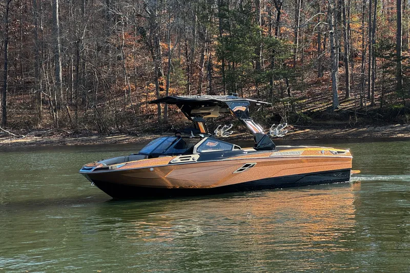 Slide: The Image of 2025 Centurion Ri265 boat cruising on a serene lake with forested background. - 7