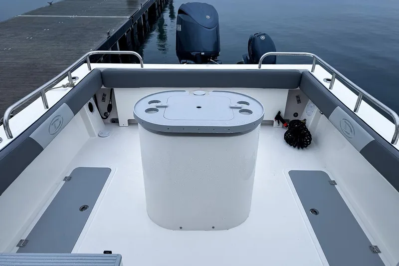 Slide: The Image of Manufacturer Provided Image: 2025 Defiance Admiral 220 EX boat interior with seating and storage, docked by the water. - 4