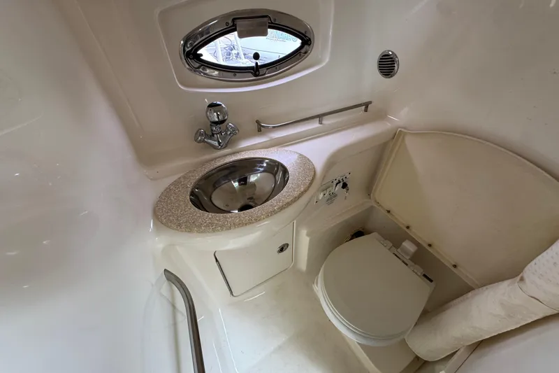 Slide: The Image of 2009 Chaparral Signature 290 boat bathroom with sink, toilet, and porthole window. - 17