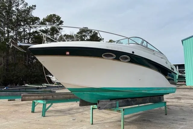 The Image of 2001 Crownline 242 CR boat on dry dock, green and white hull, outdoor setting. - 0