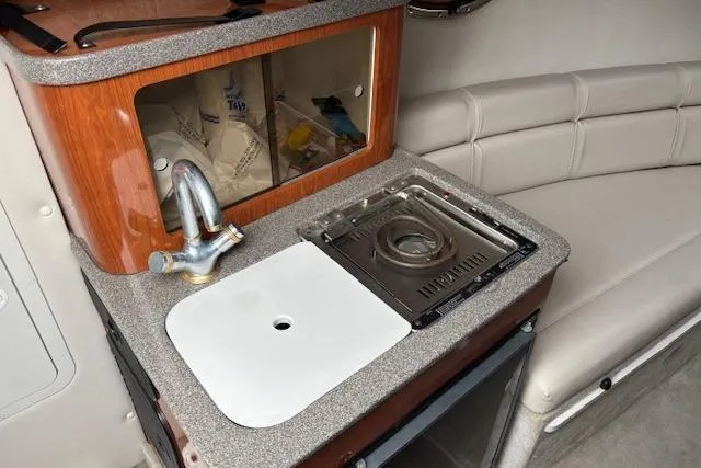 Slide: The Image of 2001 Crownline 242 CR boat interior with kitchenette, featuring sink and stove. - 11