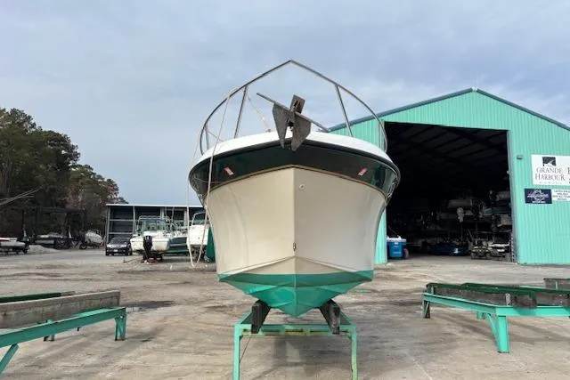 Slide: The Image of 2001 Crownline 242 CR boat on stands at a marina with green building. - 2