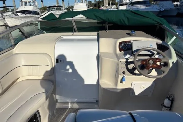Slide: The Image of 2001 Crownline 242 CR boat cockpit with steering wheel and seating, docked at marina. - 32