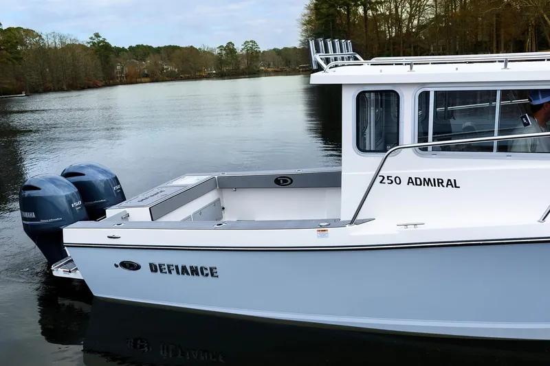 Slide: The Image of Manufacturer Provided Image: 2025 Defiance Admiral 250 EX boat on a serene lake with twin Yamaha engines. - 2