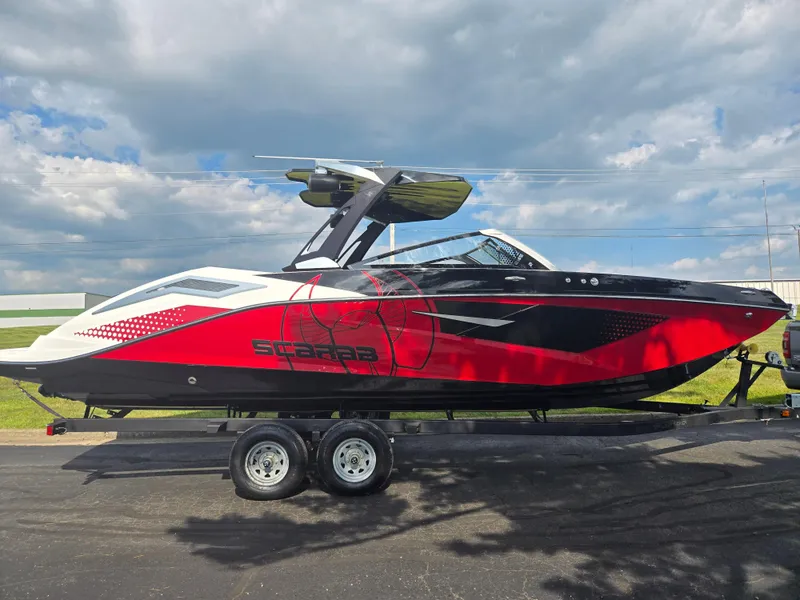 Slide: The Image of 2021 Scarab 285 ID boat in red and black on a trailer, under a cloudy sky. - 4