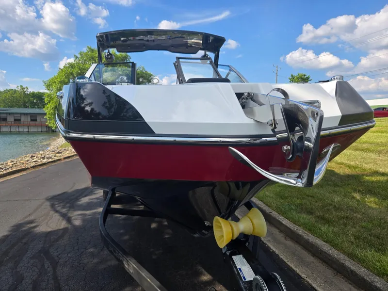 Slide: The Image of 2021 Scarab 285 ID boat on trailer, parked near a lake under a blue sky. - 6