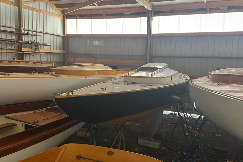 Slide: The Image of Classic 1919 Dark Harbor 17 sailboat in storage, surrounded by other vintage boats. - 2