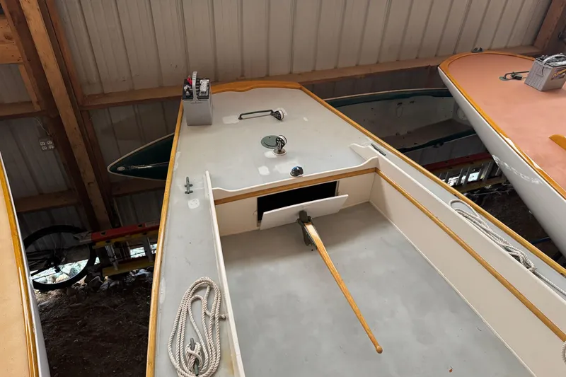 Slide: The Image of Classic 1919 Dark Harbor 17 sailboat interior with wooden tiller and ropes in storage. - 3