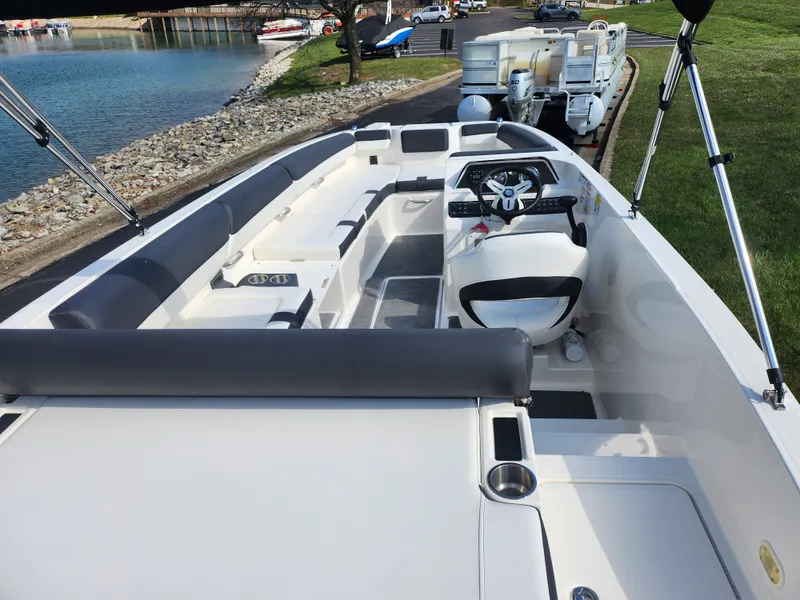 Slide: The Image of 2021 Bayliner DX 2000 boat interior with seating and steering wheel, docked by a lake. - 11