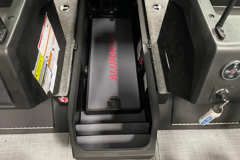 Slide: The Image of 2025 Alumacraft Trophy 185X Sport boat interior with storage compartment and control panel. - 7