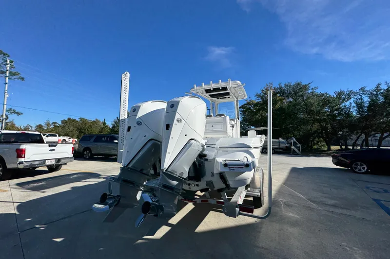 Slide: The Image of 2026 Caymas 281 HB boat with dual outboard motors in a sunny parking lot. - 15