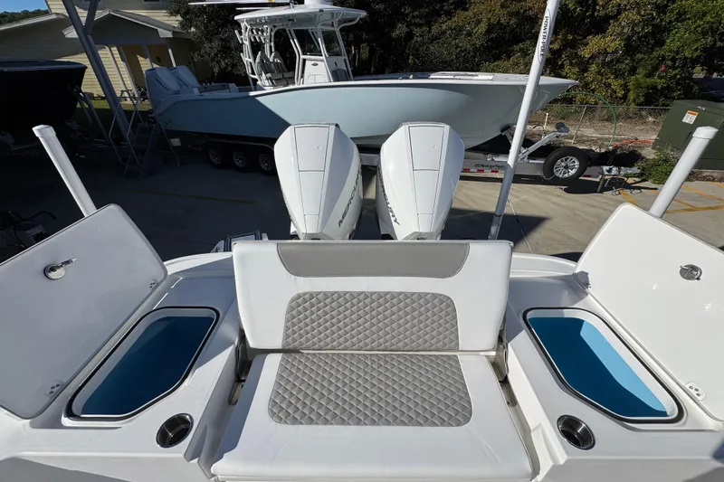 Slide: The Image of 2026 Caymas 281 HB boat with dual engines and cushioned seating, parked outdoors. - 40