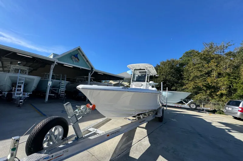 Slide: The Image of 2026 Caymas 281 HB boat on trailer at dealership under clear blue sky. - 5