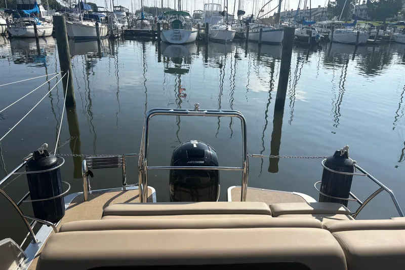 Slide: The Image of 2024 Harris HCX23 boat docked at marina with calm water and surrounding vessels. - 7