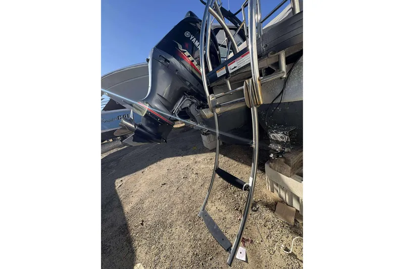 Slide: The Image of 2020 Godfrey Monaco 25 boat with Yamaha outboard motor and metal ladder on dry ground. - 13