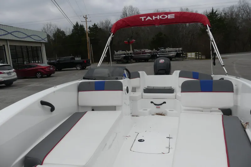 Slide: The Image of 2024 Tahoe T18 boat with red canopy and spacious seating, parked outdoors. - 5