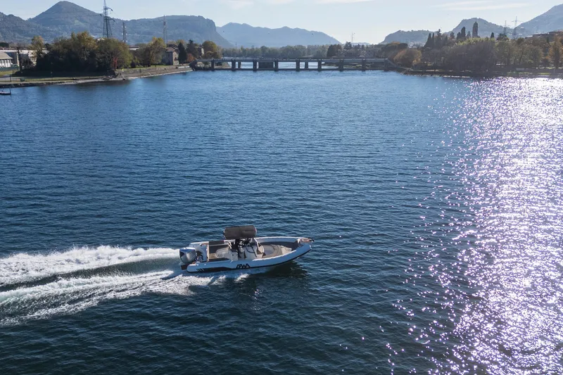 Slide: The Image of A BWA GTO 308 boat cruising on a scenic lake with mountains in the background. - 13