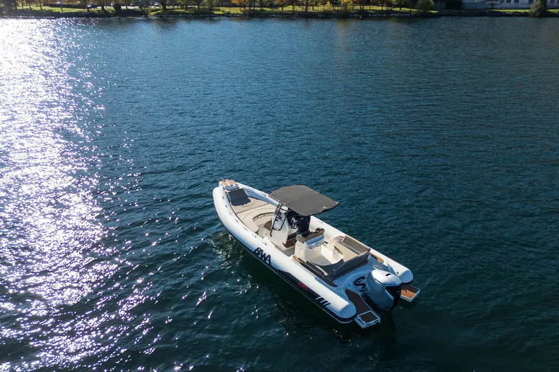 Slide: The Image of 2026 BWA GTO 308 boat cruising on a sunlit lake with scenic shoreline. - 4