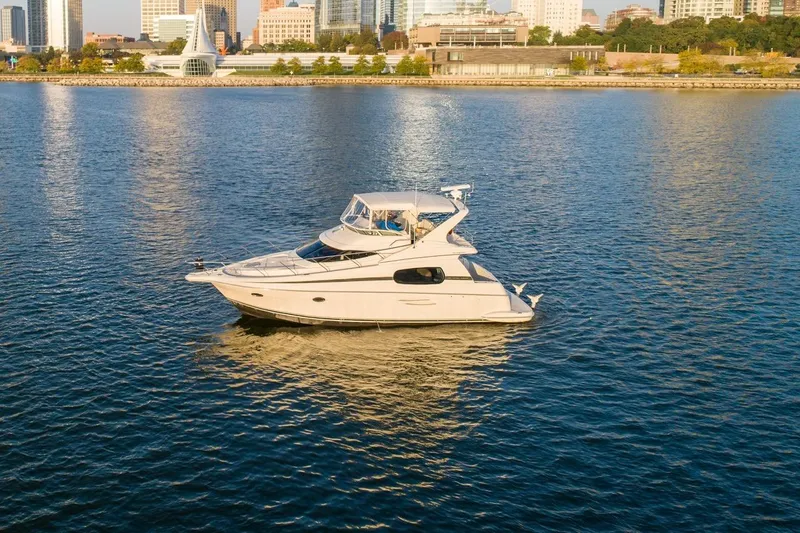 The Image of 2003 Silverton 410 Sport Bridge yacht on calm water near city skyline. - 0